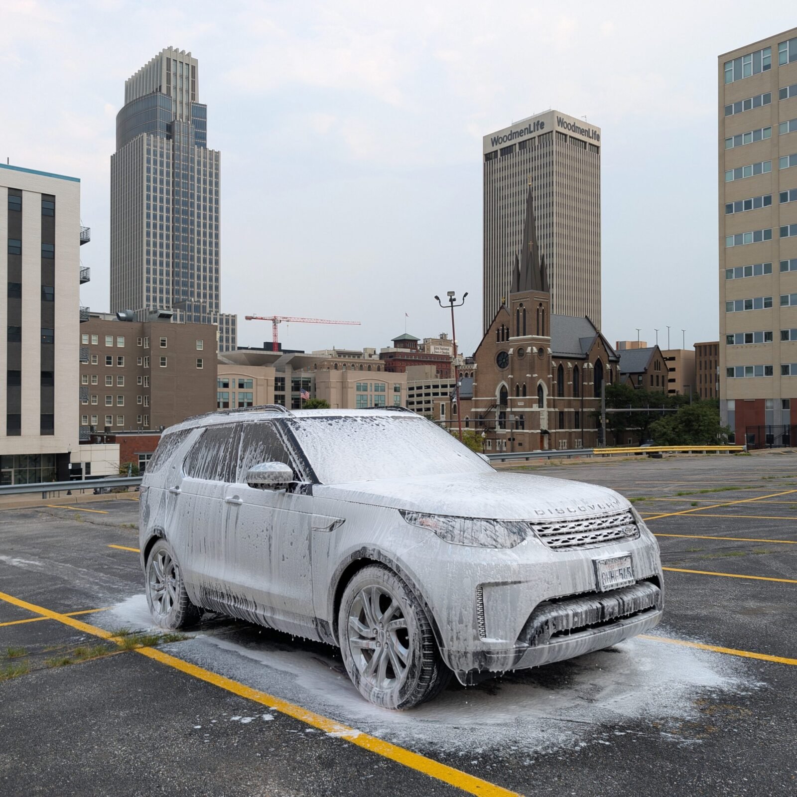 Driven Aesthetics Mobile Detail performing an exterior detail on a Land Rover Discovery with Omaha's Downtown Skyscrapers in the background in a open parking lot
